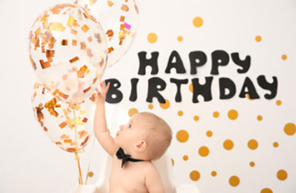Ребенок тянется к воздушным шарам, сверху надпись "Happy birthday"